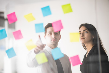 Wall Mural - Two businesspeople discussing and planning concept. Front of glass wall marker and stickers. Startup office.