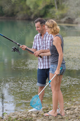 Plakat piękne młode małżeństwo razem połowów nad jeziorem
