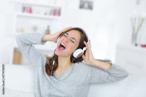 Plakat kobieta ze słuchawkami śpiewając podczas słuchania muzyki