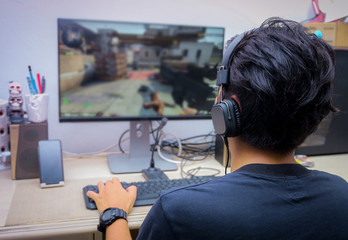 back view of young gamer playing fps video games at home