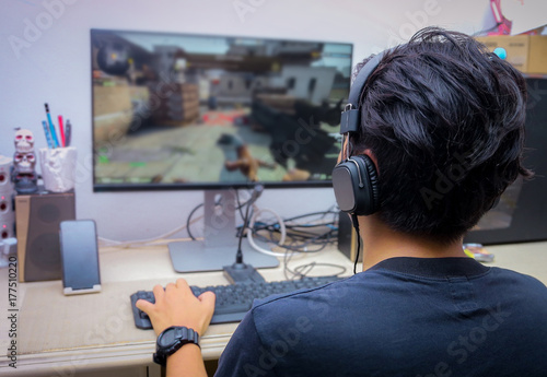 Back view of young gamer playing FPS video games at home Canvas Print