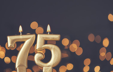 Wall Mural - Gold number 75 celebration candle against blurred light background