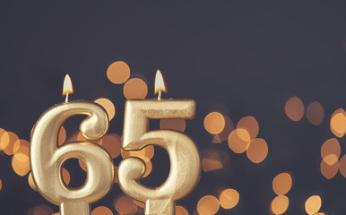 Wall Mural - Gold number 65 celebration candle against blurred light background