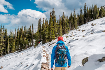 Wall Mural - Tourist with backpack hiking on snowy trail