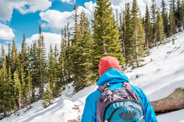 Wall Mural - Tourist with backpack hiking on snowy trail