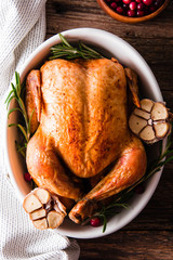 Wall Mural - Roasted chicken with cranberries, rosemary and garlic  on wooden table, top view.