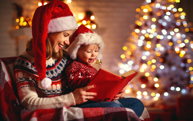 Wall Mural - christmas eve. family mother and baby reading magic book at home .