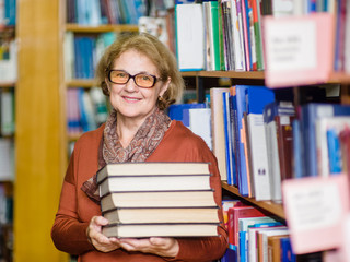 Wall Mural - Happy senior woman with books in library