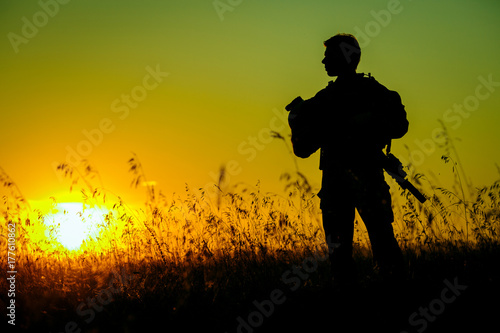 Plakat żołnierz wojskowy z bronią o zachodzie słońca. strzał, trzymając pistolet, kolorowe niebo. koncepcja wojskowa.