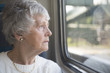 One senior woman looking out of the window on a train 