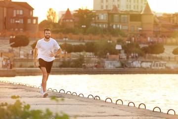 Wall Mural - Handsome young man running near river