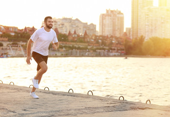 Wall Mural - Handsome young man running near river