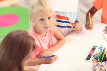 Canvas Print - Cute girl with friends painting at table indoor