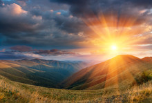 Panoramic Landscape Of Fantastic Sunset In The Mountains. View Of The Autumn Hills Lit By The Rays Of The Evening Sun. Dramatic Clouds Over Sky.