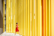 © rh2010 - Woman in red dress walking on the modern yellow building wall background. General plan with abstract geometric composition