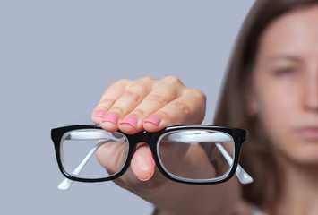 Canvas Print - A woman holds a glasses in her hand. Eye care and the choice the means to improve vision.