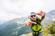 Portrait of a young traveler with a beard and a backpack in a cap and sunglasses against the background of the Caucasus Mountains