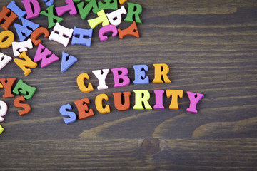 Wall Mural - cyber security. various colored wooden letters on a dark plate.