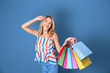 © Africa Studio - Beautiful woman with paper bags on blue background