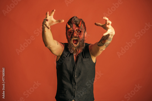 Obraz na płótnie Halloweenowy mężczyzna diabeł z żywymi trup rękami na pomarańczowym tle