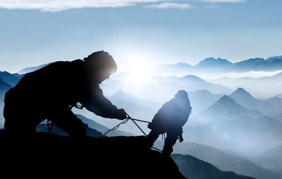 Fototapete - Hilfe beim Aufstieg - Bergsteiger auf einem Gipfel im Hochgebirge 