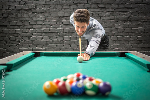 Plakat Szczęśliwy biznesowy mężczyzna bawić się grę bilard i przygotowywać łamać ostrosłup piłki na basenu stole.