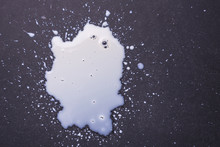 White Milk Spilled And Splash On The Dark Floor Surface.