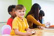 © weedezign - Caucasian boy ethnicity kid smiling white learning in classroom with friends and teacher  in kindergarten school, education concept.