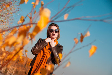 girl on a background of nature sky and yellow leaves in autumn