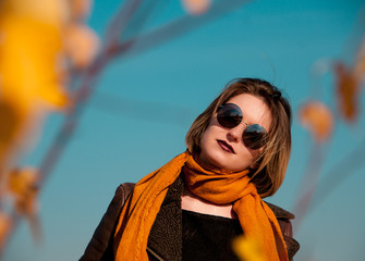 girl on a background of nature sky and yellow leaves in autumn