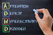 ADHD – attention deficit hyperactivity disorder handwritten by woman on blackboard