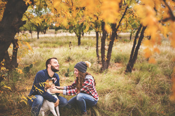 Cute couple playing with their dog in the fall leaves