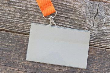 Blank ID card tag with ribbon on wooden background