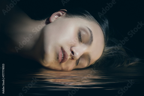 Zdjęcie XXL piękna kobieca głowa z zamkniętymi oczami leżącego na wodzie z odbicia