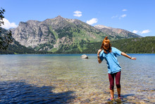 Girl Wading In Clear Mountain Lake