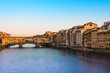The Ponte Vecchio bridge over the Arno River at sunset.