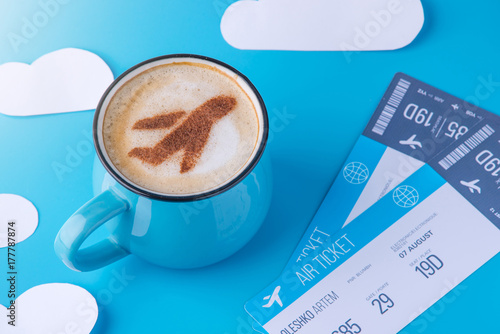Plakat Filiżanka cappuccino z obrazem samolotu na piance i biletach. Niebieskiego nieba tło z papierowymi chmurami