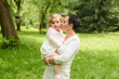 © Nestyda - family, children and happy people concept - happy little girl hugging her mother over green background