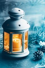 Close-up photo of a blue vintage lantern with burning candle among Christmas decoration. Concept of New Year and wintertime.