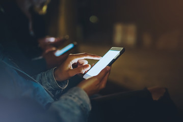 People together pointing on screen smartphone on background bokeh light in night atmospheric city, group hipsters friends using in hands mobile phone, street online wi-fi internet concept