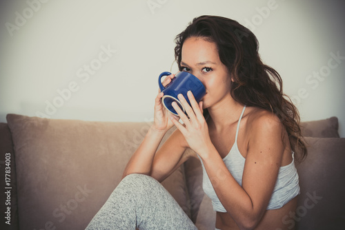 Plakat Picie, uśmiechając się na kanapie nastolatka kobieta z kubkiem