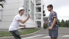 Two Teenagers On Street Practicing New Kendama Moves