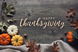 Fototapeta  - Happy Thanksgiving script with pumpkins and leaves over dark wooden background