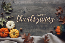 Happy Thanksgiving Script With Pumpkins And Leaves Over Dark Wooden Background