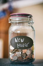 Saving Money Jar With Label Saying 'new House'