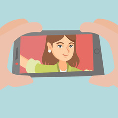 Poster - Young caucasian woman making selfie. Smiling woman making selfie with a cellphone. Woman using her smartphone to take selfie photo. Woman taking photo. Vector cartoon illustration. Square layout.