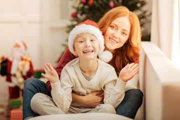 Wall Mural - Charming mother hugging her son tightly on sofa