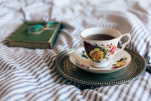 Black Tea In China Cup On Vintage Tray With Closed Book And Glasses