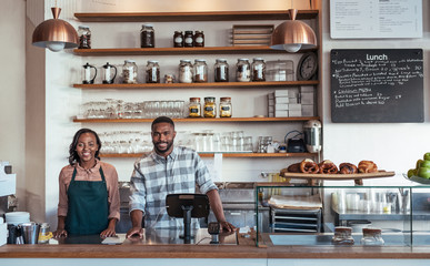 Wall Mural - Two smiling African entrepreneurs standing behind their bakery counter