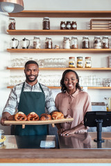 Wall Mural - Two smiling African bakery owners standing behind their counter